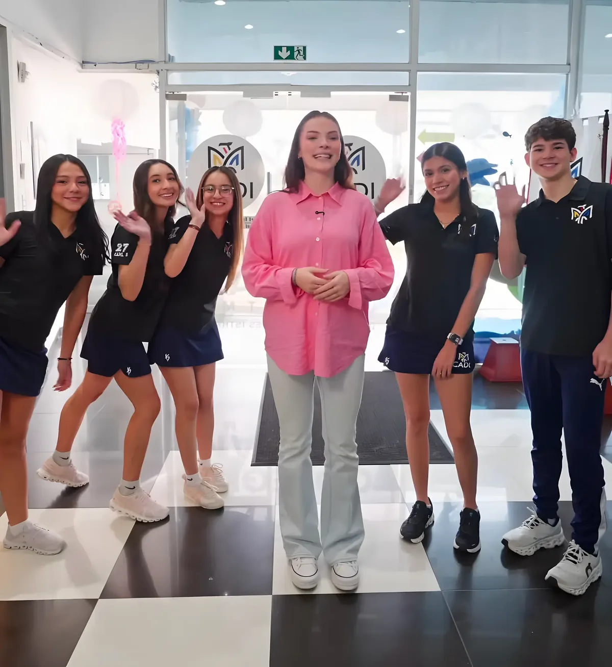CADI students and a teacher waving in the school entrance hall